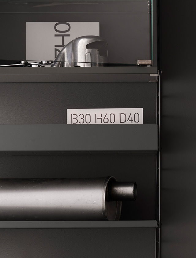 String Regal System präsentiert sich in einem eleganten Dunkelgrau mit Metallfachböden, die eine Tiefe von 30 cm aufweisen. Die Fachböden sind in zwei Varianten gestaltet: mit einem niedrigen Rand von 2 cm sowie einer höheren Variante mit 7 cm Randhöhe. Diese Kombination sorgt für eine flexible Nutzung und eine klare, moderne Ästhetik.