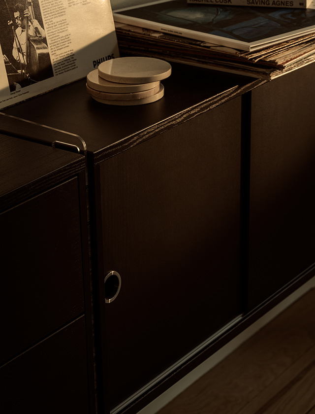 String Furniture Schrank aus schwarz gebeizter Esche mit transparentem Plex-Seitenteil, dekoriert mit Schallplatten und Wohnaccessoires.