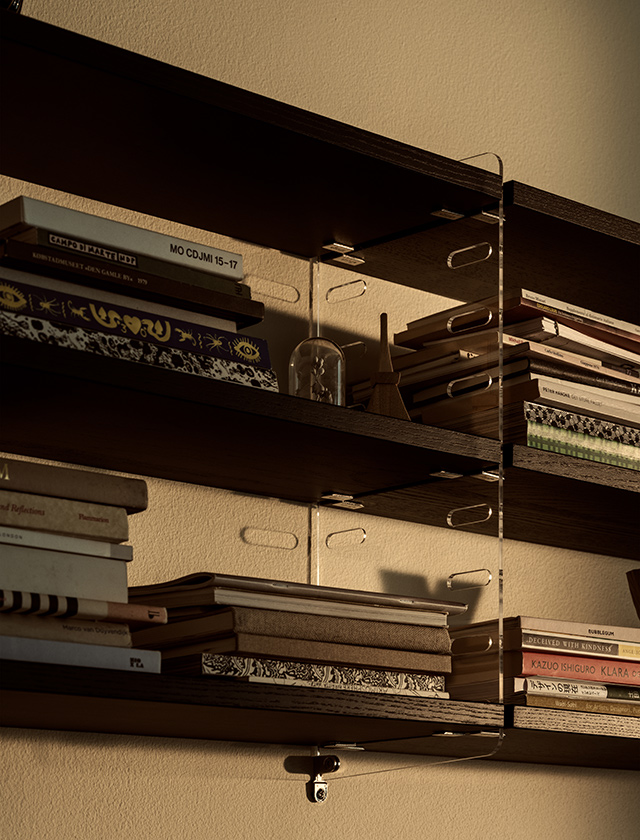 Dunkles String Furniture Wandregal aus schwarz gebeizter Esche mit transparenten Plex-Seitenteilen und Büchern auf mehreren Regalböden.