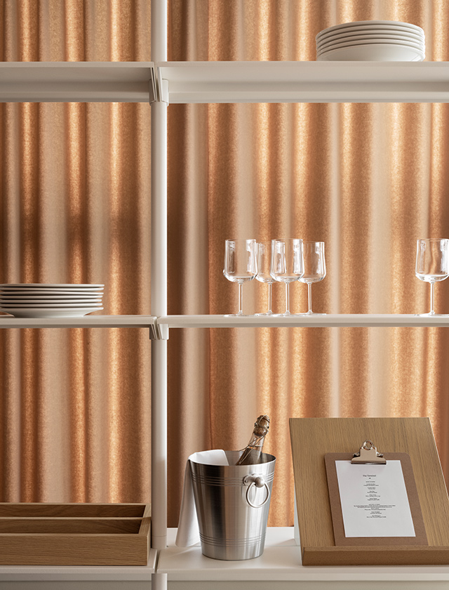 Im unteren Bereich bietet ein Schrank mit Klapptüren zusätzlichen Stauraum, in dem sich verschiedene Gegenstände wie Glasflaschen verstauen lassen. Die Kombination aus offenen und geschlossenen Bereichen macht das Regal besonders funktional und vielseitig einsetzbar. Durch die höhenverstellbaren Füße steht es stabil auf unterschiedlichen Bodenbelägen.