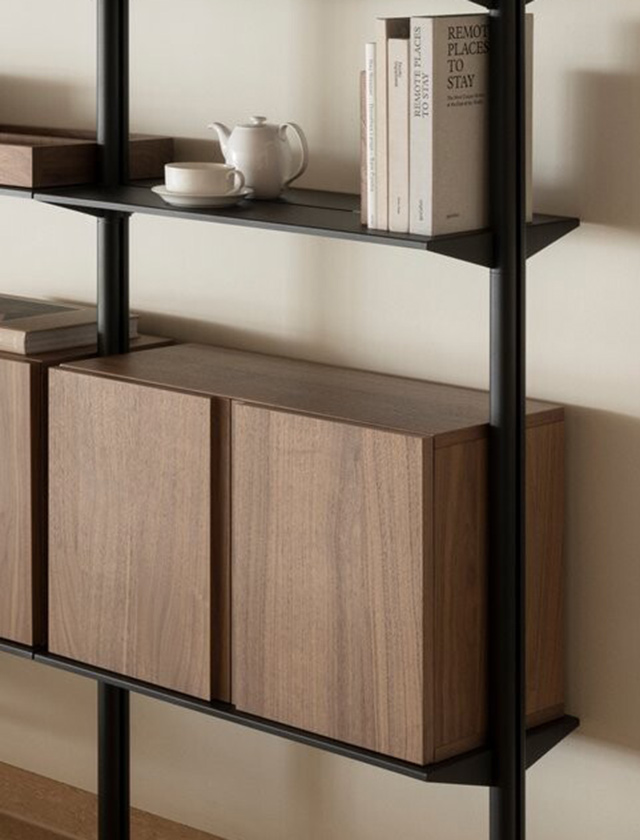 Pira Regalsystem von String Furniture in Walnuss-Ausführung, mit integriertem Aktenschrank zur Aufbewahrung von Aktenordnern. Das Regalelement kombiniert offene Ablageflächen mit geschlossenen Holztüren in eleganter Holzoptik und schwarzem Metallrahmen – ideal für stilvolle und funktionale Büro- oder Wohnräume.