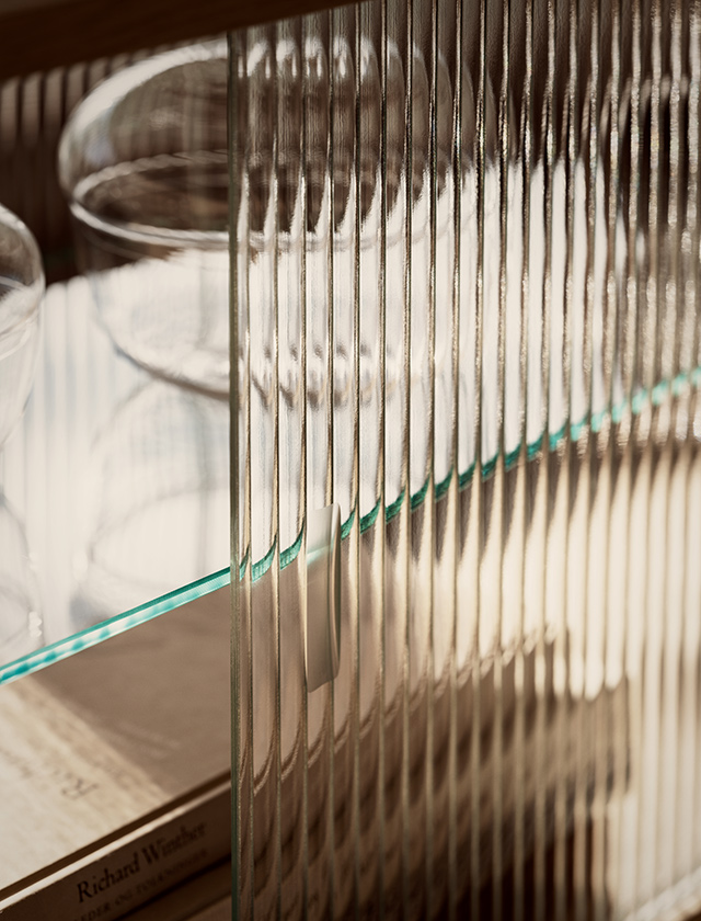 Wandmontierter Pira Vitrinenschrank von String Furniture mit Riffelglas-Schiebetür vorne und Glasrückwand