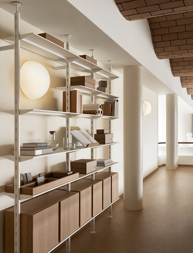 Hier trifft klare Linienführung auf wohnliche Materialien. Das Pira G2 Regal zieht sich elegant von Boden bis Decke und schafft mit seinen weißen Pfosten und Böden eine ruhige, offene Atmosphäre. Unten sorgen die Schränke aus Eiche mit ihren glatten Klapptüren für praktischen Stauraum. Ob Bücher, Boxen oder schöne Objekte – alles ist gut aufgehoben und schön in Szene gesetzt. Besonders in größeren Räumen oder offenen Grundrissen kommt dieses System richtig zur Geltung. Es wirkt fast wie ein Möbelstück, das den Raum mitgestaltet.